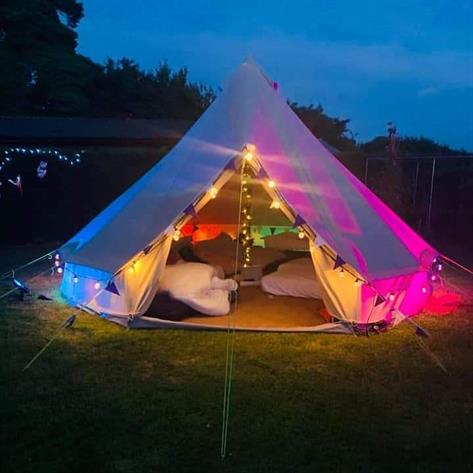 5m bell tent lit in green and pink